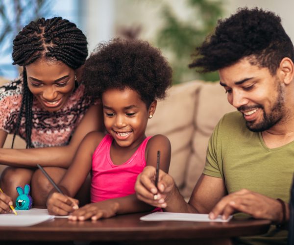Mom and dad drawing with their daughter. African american family spending time together at home.