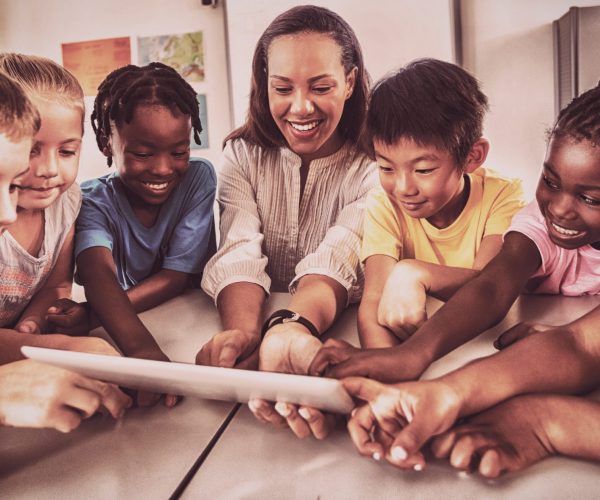 Smiling students and teacher using a tablet computer
